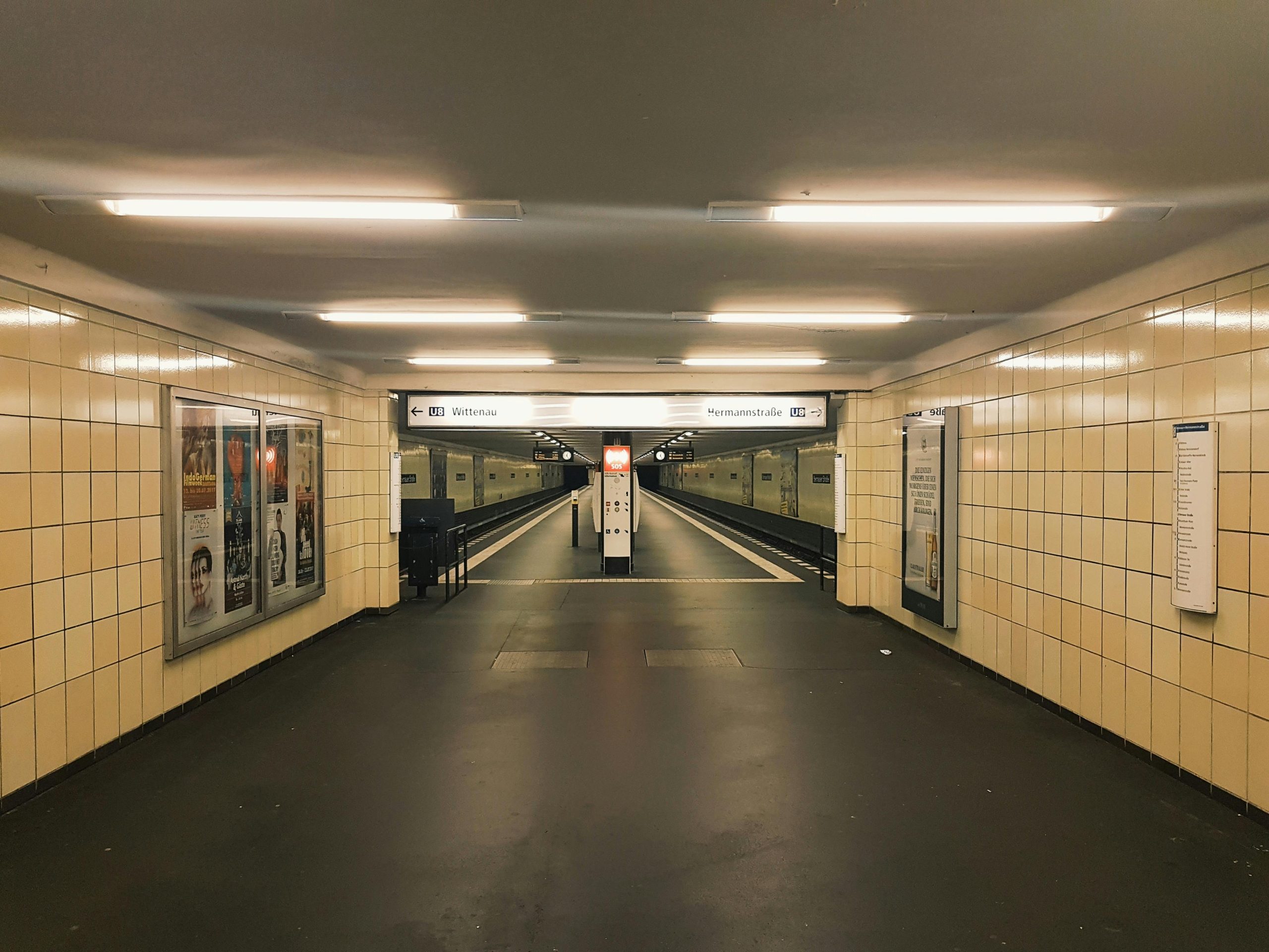 Deserted hallway of a Berlin subway station with yellow tiles and bright lighting.